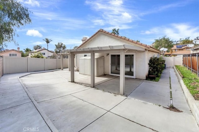 rear view of property featuring a patio area, a tiled roof, a fenced backyard, and stucco siding