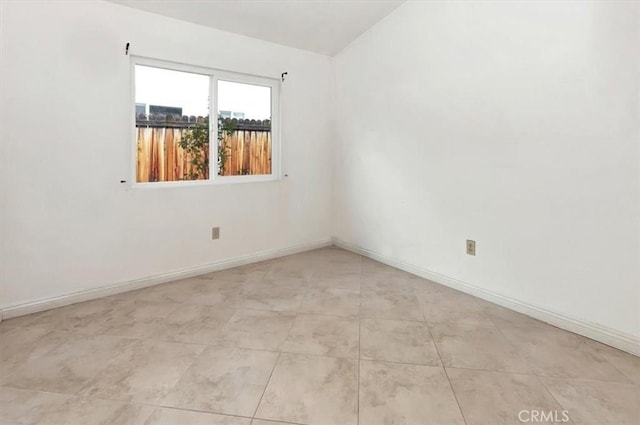 spare room featuring light tile patterned floors, baseboards, and lofted ceiling