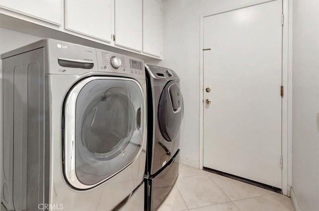 clothes washing area with washer and dryer, baseboards, cabinet space, and light tile patterned flooring