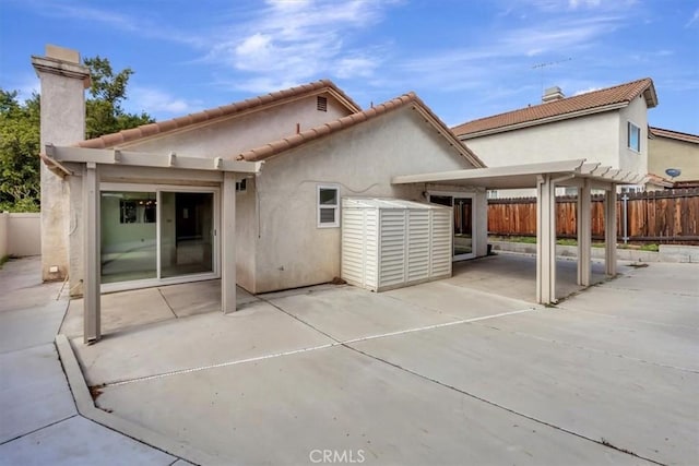 rear view of house with stucco siding, a pergola, a patio, and fence