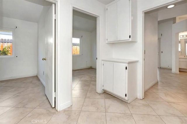 hallway featuring light tile patterned floors and baseboards