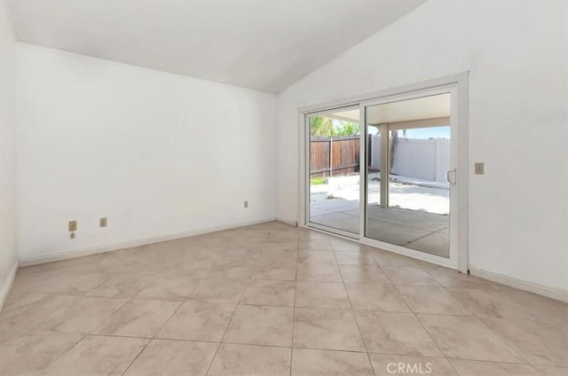 empty room featuring light tile patterned floors, baseboards, and vaulted ceiling