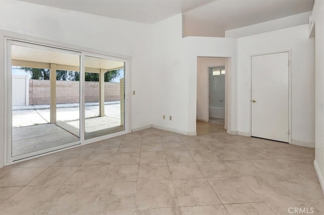 spare room with light tile patterned floors and baseboards