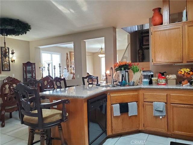 kitchen featuring brown cabinets, a sink, a kitchen breakfast bar, black dishwasher, and light tile patterned floors