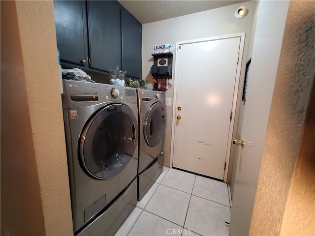 laundry area featuring light tile patterned floors, cabinet space, and washer and clothes dryer