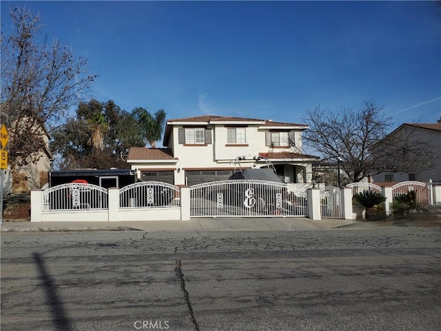 view of front of home featuring a fenced front yard, stucco siding, a tiled roof, and a gate