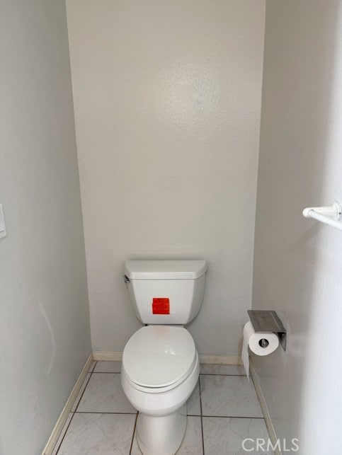 bathroom with marble finish floor, toilet, and baseboards