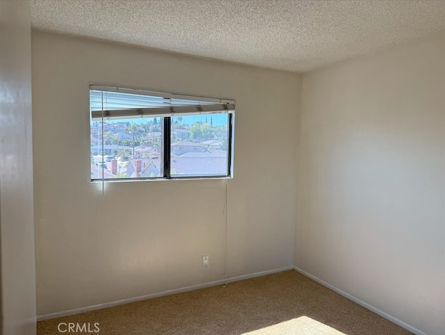 spare room featuring a textured ceiling, carpet flooring, and baseboards