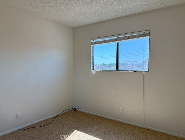 unfurnished room with carpet, a textured ceiling, and baseboards