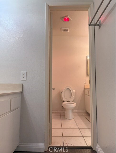 bathroom with tile patterned flooring, toilet, vanity, visible vents, and baseboards