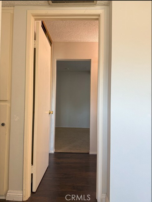 hall with dark wood-style floors and a textured ceiling