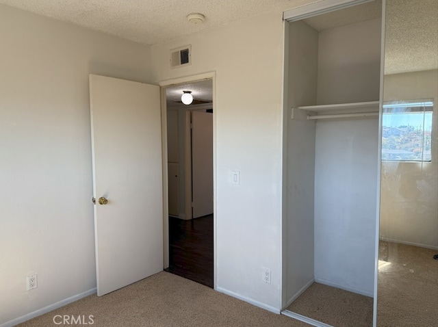 unfurnished bedroom featuring carpet floors, visible vents, a textured ceiling, and baseboards