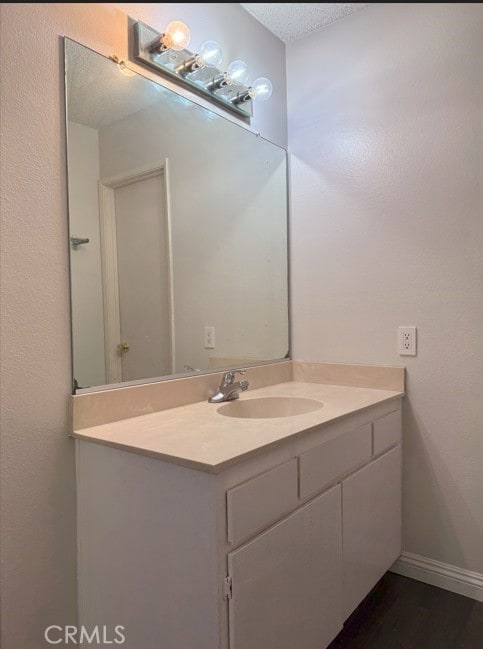 bathroom featuring baseboards, wood finished floors, a textured ceiling, and vanity