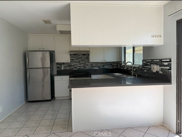 kitchen featuring gas range oven, light tile patterned floors, dark countertops, freestanding refrigerator, and a sink