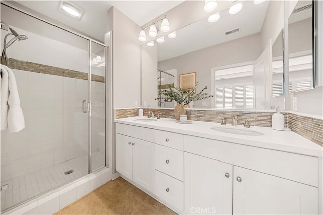 bathroom with double vanity, a stall shower, visible vents, and a sink