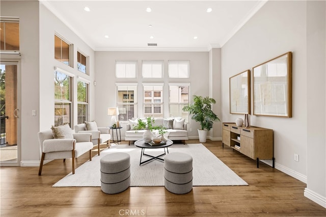 living room with crown molding, visible vents, a high ceiling, wood finished floors, and baseboards