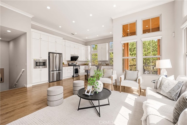 living room with ornamental molding, recessed lighting, and light wood-style flooring