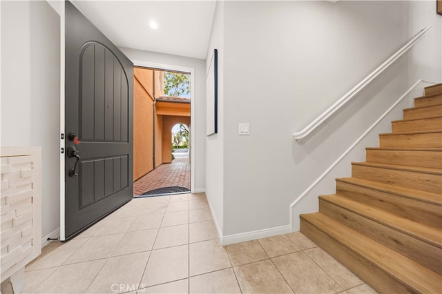 foyer entrance featuring stairs, baseboards, and light tile patterned floors