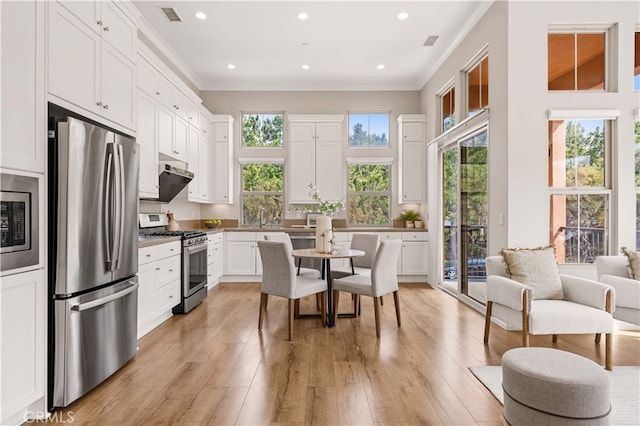 kitchen featuring stainless steel appliances, white cabinets, ornamental molding, and visible vents