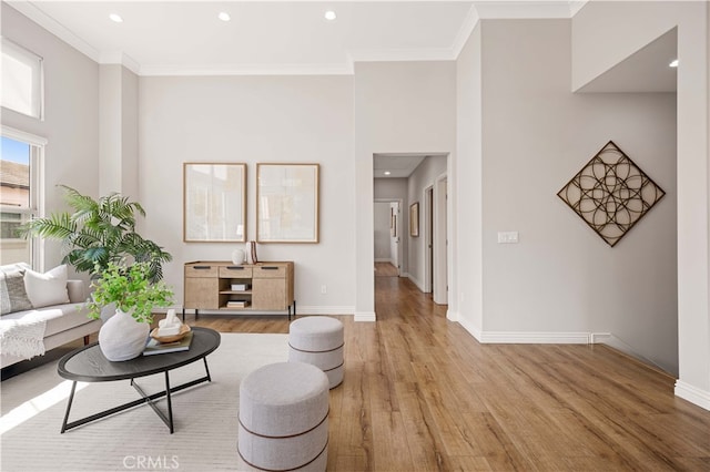 living room featuring recessed lighting, a towering ceiling, baseboards, light wood finished floors, and crown molding