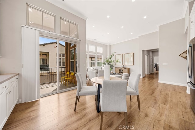 dining area featuring crown molding, recessed lighting, light wood-style flooring, a high ceiling, and baseboards