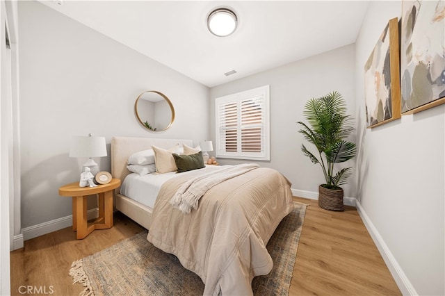 bedroom featuring wood finished floors, visible vents, and baseboards