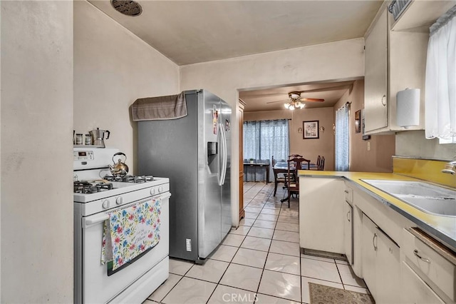 kitchen with a ceiling fan, white gas stove, light tile patterned flooring, a sink, and stainless steel fridge