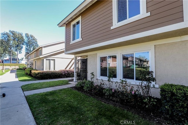 view of side of property featuring a lawn and stucco siding