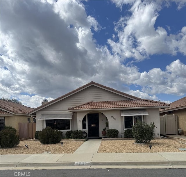 view of front of property featuring a tiled roof, an attached garage, fence, and stucco siding