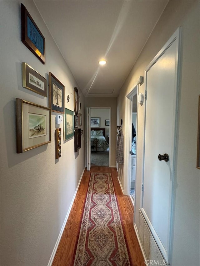 corridor with baseboards, visible vents, and wood finished floors