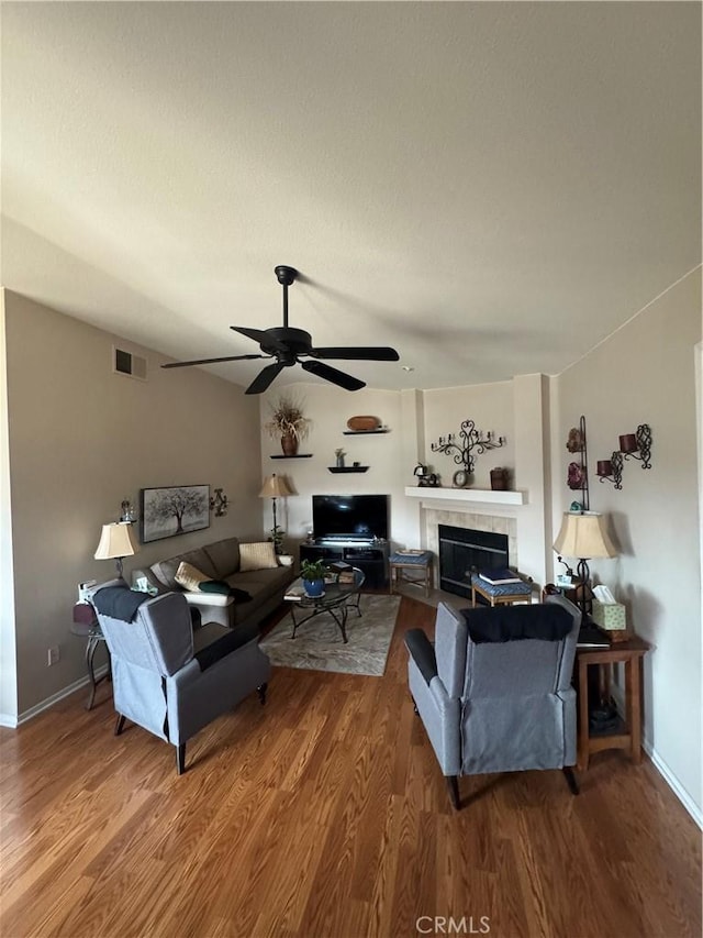 living room with visible vents, a ceiling fan, wood finished floors, vaulted ceiling, and a fireplace