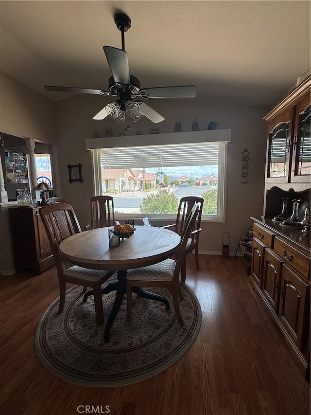 dining room with dark wood-style floors, a wealth of natural light, vaulted ceiling, and a ceiling fan