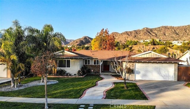 ranch-style house with a front yard, concrete driveway, a mountain view, and an attached garage