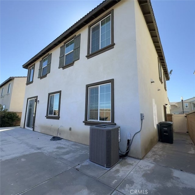 rear view of house with central AC, a patio, fence, and stucco siding