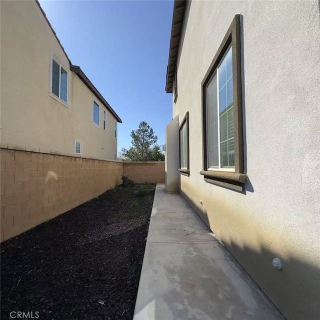 view of side of home with a fenced backyard and stucco siding