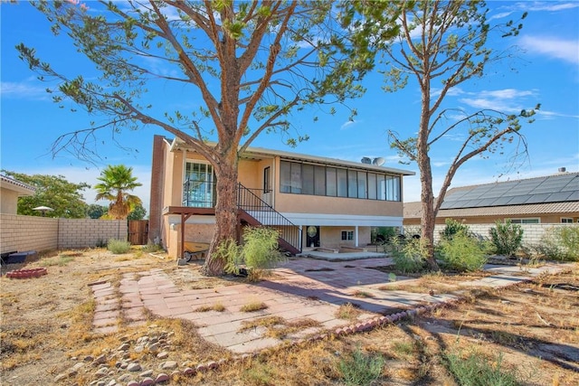 view of front of property featuring a patio area, fence, stairway, and stucco siding