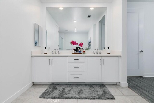 full bathroom with double vanity, an enclosed shower, baseboards, and a sink