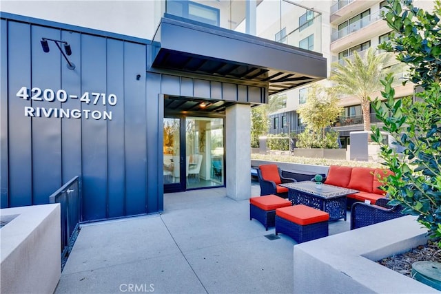 property entrance featuring a patio, board and batten siding, and outdoor lounge area