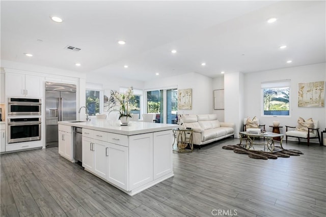 kitchen with visible vents, white cabinets, stainless steel appliances, and open floor plan