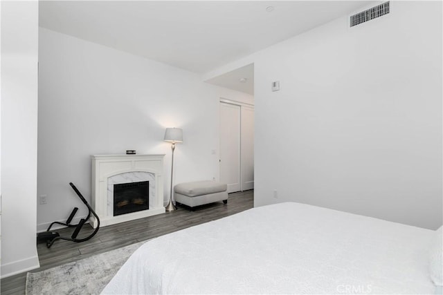 bedroom featuring visible vents, wood finished floors, baseboards, and a premium fireplace