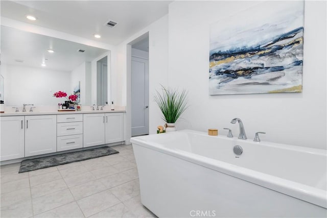 bathroom with visible vents, double vanity, a soaking tub, a sink, and tile patterned floors