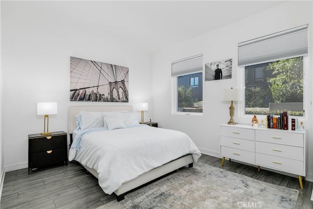 bedroom featuring baseboards, multiple windows, and wood finished floors