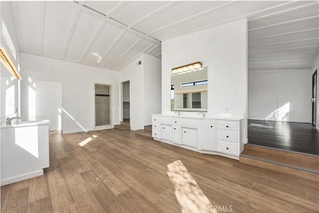 unfurnished living room featuring lofted ceiling, wood finished floors, and baseboards