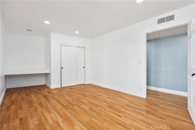 unfurnished room featuring built in desk, light wood finished floors, recessed lighting, visible vents, and baseboards