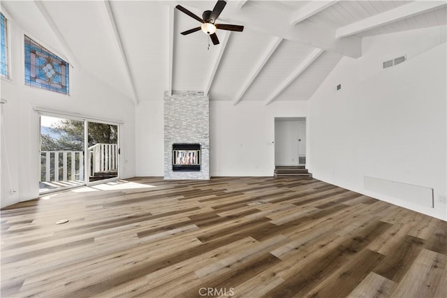 unfurnished living room with visible vents, a ceiling fan, wood finished floors, beamed ceiling, and a fireplace