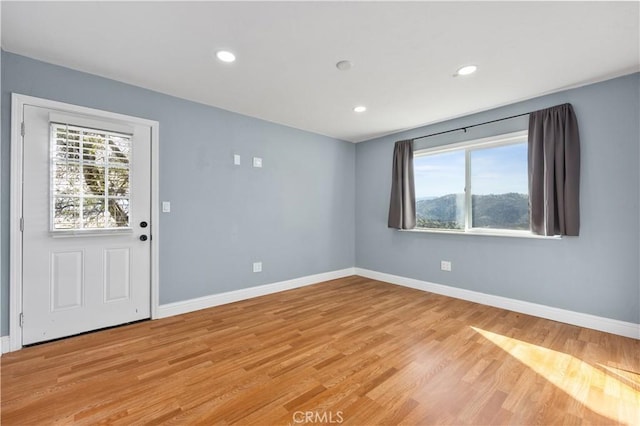 empty room featuring light wood-type flooring, baseboards, and recessed lighting