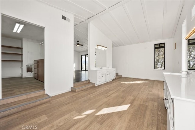 unfurnished living room with visible vents, a ceiling fan, vaulted ceiling, light wood-type flooring, and a sink