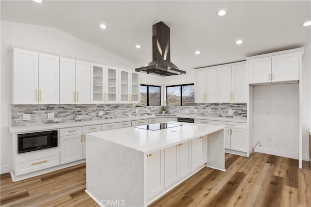 kitchen featuring lofted ceiling, black appliances, white cabinets, and exhaust hood