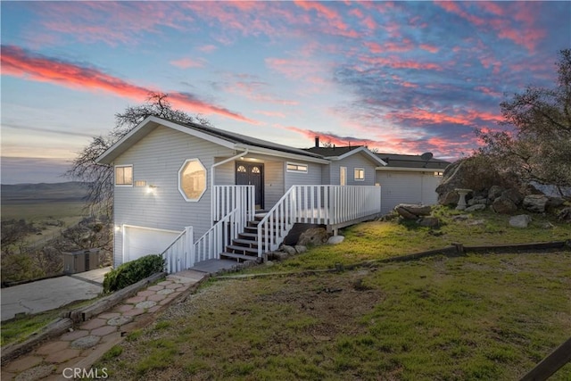 ranch-style house with a yard, driveway, stairway, and an attached garage