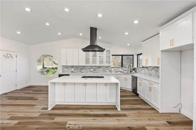 kitchen featuring lofted ceiling, island range hood, white cabinetry, light countertops, and a center island